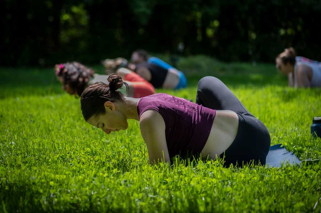 Community members doing yoga outdoors- Wellness Grind + Social Impact Level Up